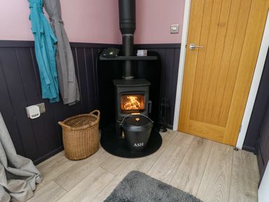 A snug with a wood stove and basket at Hares Hideaway Shepherd's Hut South Molton