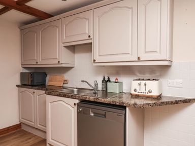 A kitchen with cabinets, sink, and appliances at Swallow Cottage in Lealholm