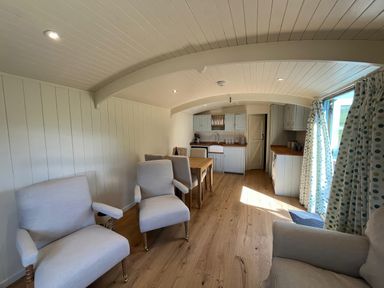 A living room with chairs and a kitchen area at The Orchard in Ringstead