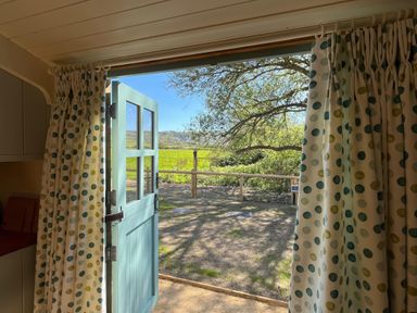 A door and curtains opening to a view of trees and a fenced field at The Orchard in Ringstead