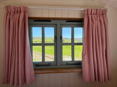 A window with striped curtains and a view at The Orchard in Ringstead
