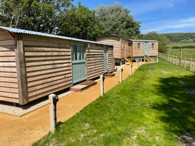 A row of cabins with doors and steps on a grassy area at The Orchard in Ringstead