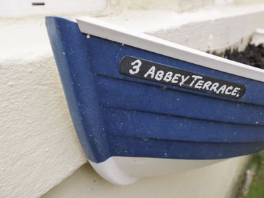 A blue miniature boat with an address plaque at The Hideaway in Whitby