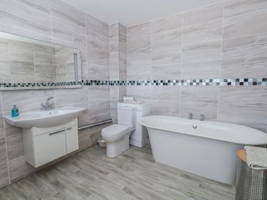 A bathroom with a bath tub, toilet, and sink at Flat 17 Golden Gates in Poole