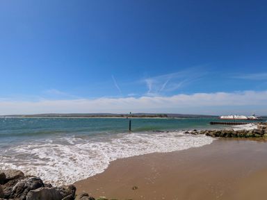 A beach view with water and a ferry at Flat 17 Golden Gates in Sandbanks