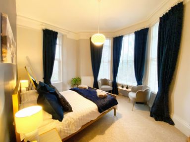 A bedroom with a bed and chairs at 2A Redcliffe in Torquay