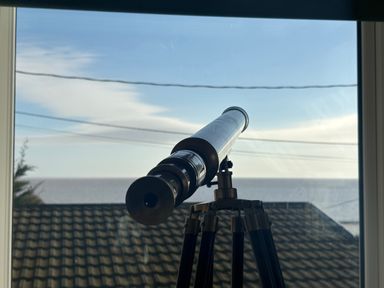 A telescope mounted on a tripod looking out the window at Seaview in Pakefield