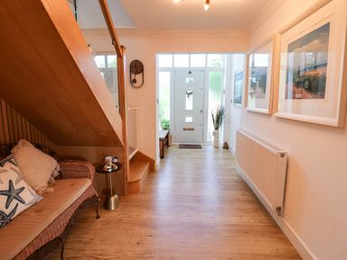 A hallway with a staircase and a sofa at Seaview in Pakefield