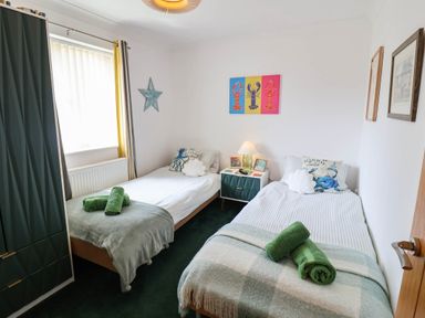 A bedroom with two beds and a table at Seaview in Pakefield