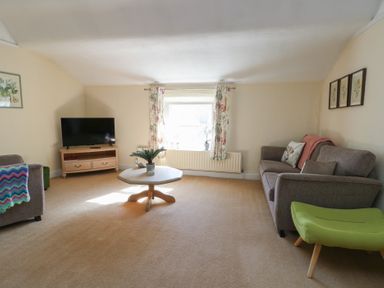 A living room with a television and sofa at Castle Gardens Apartment Beaumaris