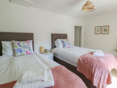 A bedroom with two beds and a nightstand at Castle Gardens Apartment Beaumaris