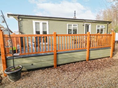 A house with a wooden fence and gravel area at The Nest Lodge 55 Grantham