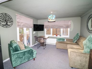 A snug with a sofa and armchair and a television at The Nest Lodge 55 Grantham