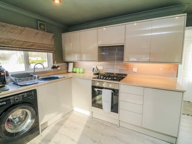 A kitchen with a washing machine, stove, and sink at The Nest Lodge 55 in Grantham