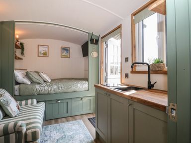 A bedroom with a bed and kitchenette at Salt Haven Shepards Hut Pevensey