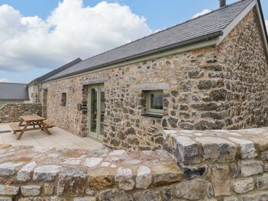 An outdoor area with a stone building and picnic table at Dairy Cottage in Oxwich