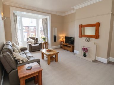 A living room with a sofa, armchair, coffee table and television at Time Out in Whitby