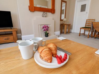 A living room with coffee cups and croissants on a table at Time Out in Whitby