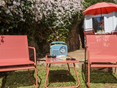 A garden with chairs, a table, a radio and a book at The Arches in Torquay