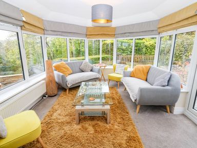 A conservatory with sofas and a coffee table at Stone Lodge near Haltwhistle