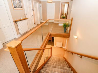 A hallway with a staircase and railing at Stone Lodge near Haltwhistle