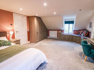 A bedroom with a bed, wardrobe, and seating area at Stone Lodge near Haltwhistle