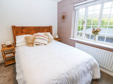 A bedroom with a bed and a vase of flowers at Stone Lodge near Haltwhistle