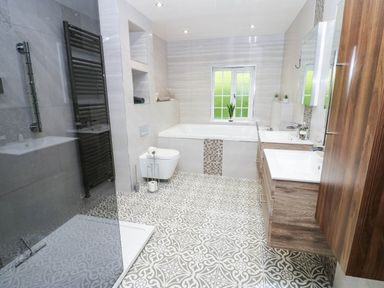 A bathroom with a bathtub, toilet, sink and mirror at Stone Lodge near Haltwhistle