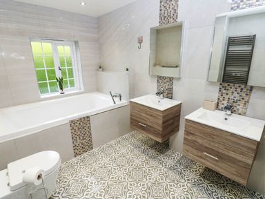 A bathroom with a bathtub and double sinks at Stone Lodge near Haltwhistle