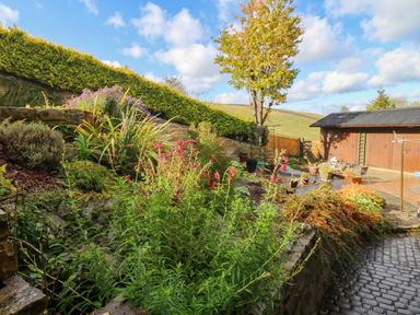 A garden with flowers and a shed at Stone Lodge near Haltwhistle