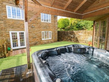 An outdoor area with a hot tub and wooden structure at Stone Lodge near Haltwhistle