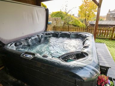 A hot tub with water in a garden area at Stone Lodge near Haltwhistle