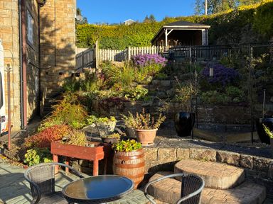 A garden with seating area and flower beds at Stone Lodge near Haltwhistle