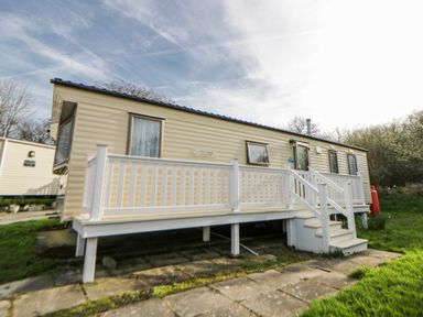 A mobile home with a deck and steps at Ger Y Mor in New Quay