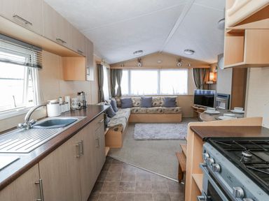 A living room with a sofa and kitchen area at Ger Y Mor in New Quay