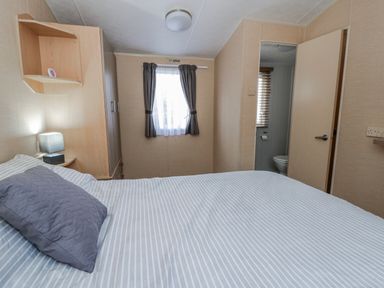 A bedroom with a bed and a bathroom door at Ger Y Mor in New Quay