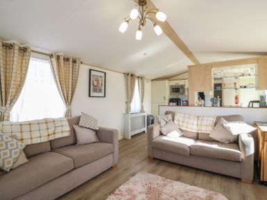 A living room with sofas and kitchen counter at 2 bed Caravan Stowmarket