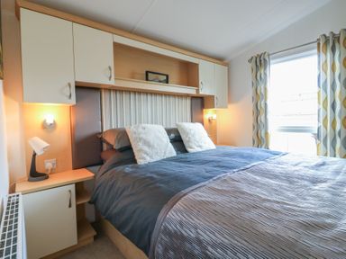 A bedroom with a bed and shelves at 2 bed Caravan in Stowmarket