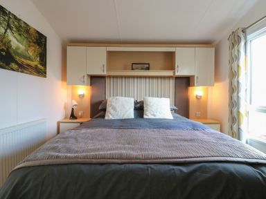 A bedroom with a bed and wall unit at 2 bed Caravan in Stowmarket