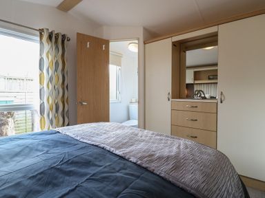 A bedroom with a bed and wardrobe at 2 bed Caravan Stowmarket