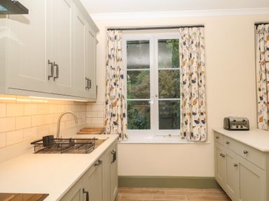 A kitchen with cabinets and a window at Lukesland Wing in Ivybridge