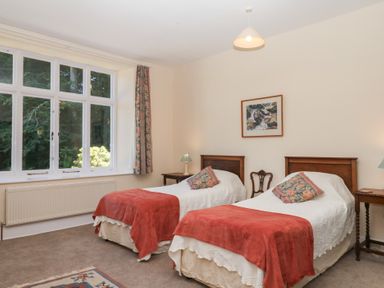 A bedroom with two beds and a window at Lukesland Wing in Ivybridge