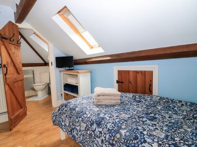 A bedroom with a bed and towels on a table at The Coach House near Charminster