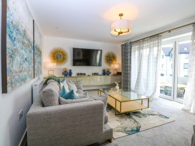 A living room with a sofa and television at 2 Glan Yr Aber in Colwyn Bay
