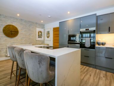 A kitchen with a kitchen island and bar stools at 2 Glan Yr Aber in Colwyn Bay
