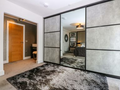 A bedroom with a mirror wardrobe and a bed at 2 Glan Yr Aber in Colwyn Bay