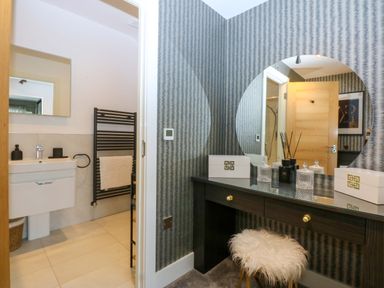 A bathroom with a vanity desk and mirror at 2 Glan Yr Aber in Colwyn Bay