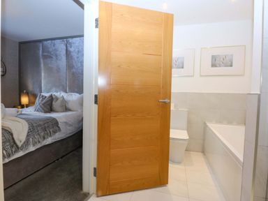 A bathroom with a toilet and bathtub near a bedroom at 2 Glan Yr Aber in Colwyn Bay