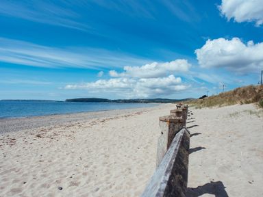 A beach with a wooden barrier near the water at Ty Pen in Nefyn