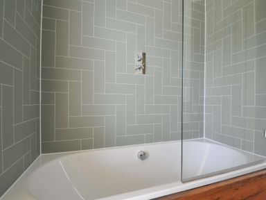 A bathroom with a bathtub and tiled wall at 4 Southern Place in Dobwalls